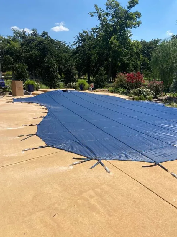 Freeform pool under a navy mesh safety cover